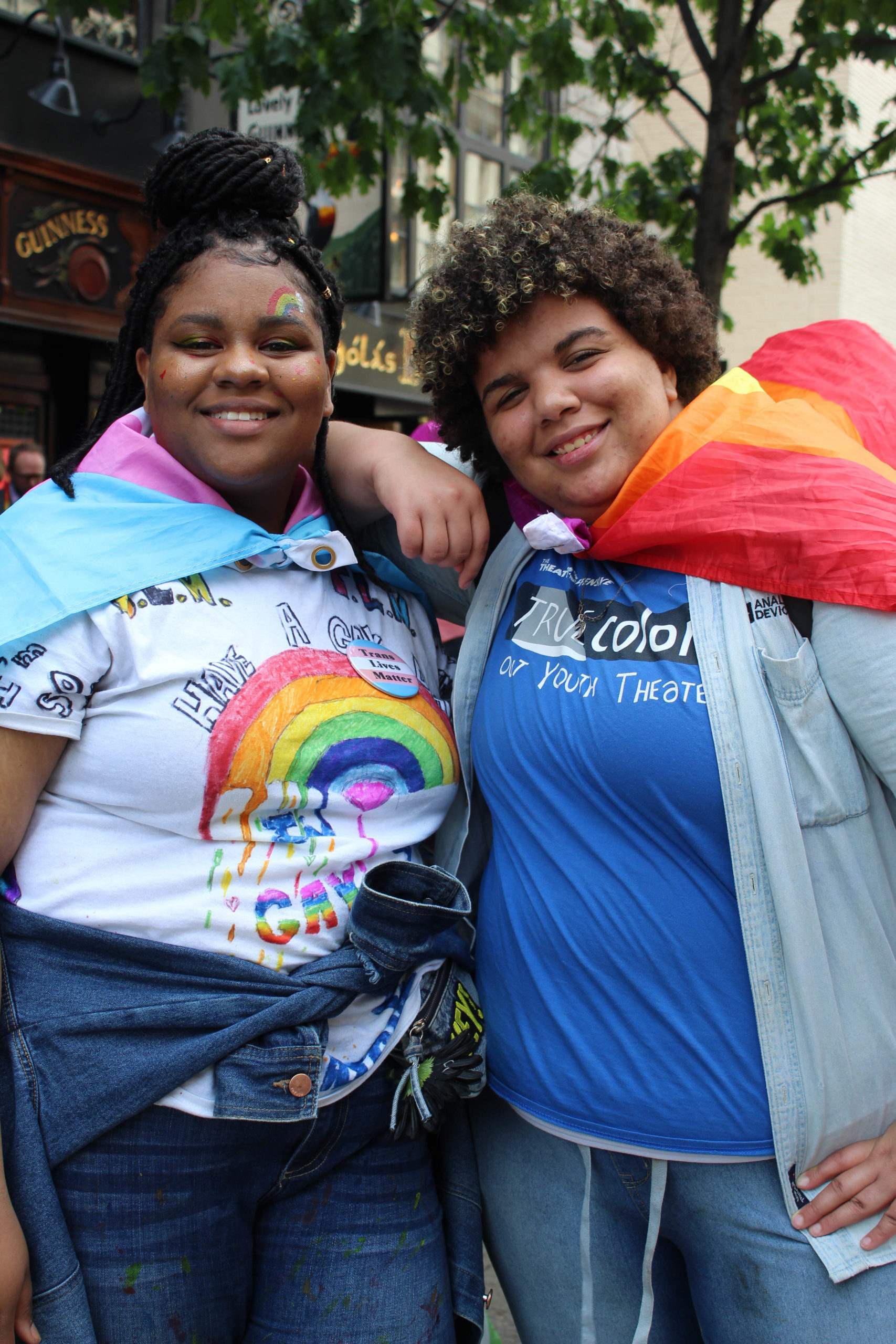 Two people posting for camera wearing Pride outfits