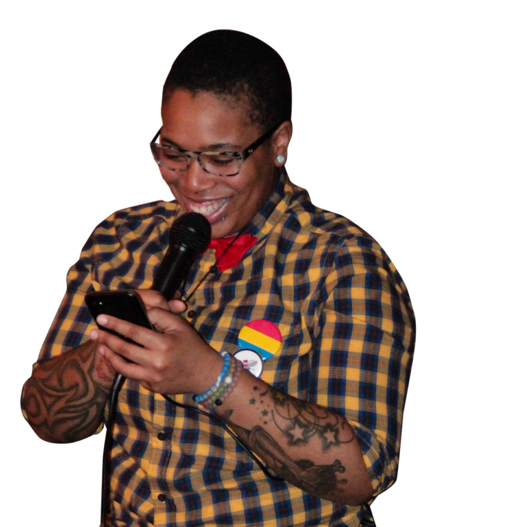 Person speaking into microphone while looking at phone and wearing bee and pansexual flag pins